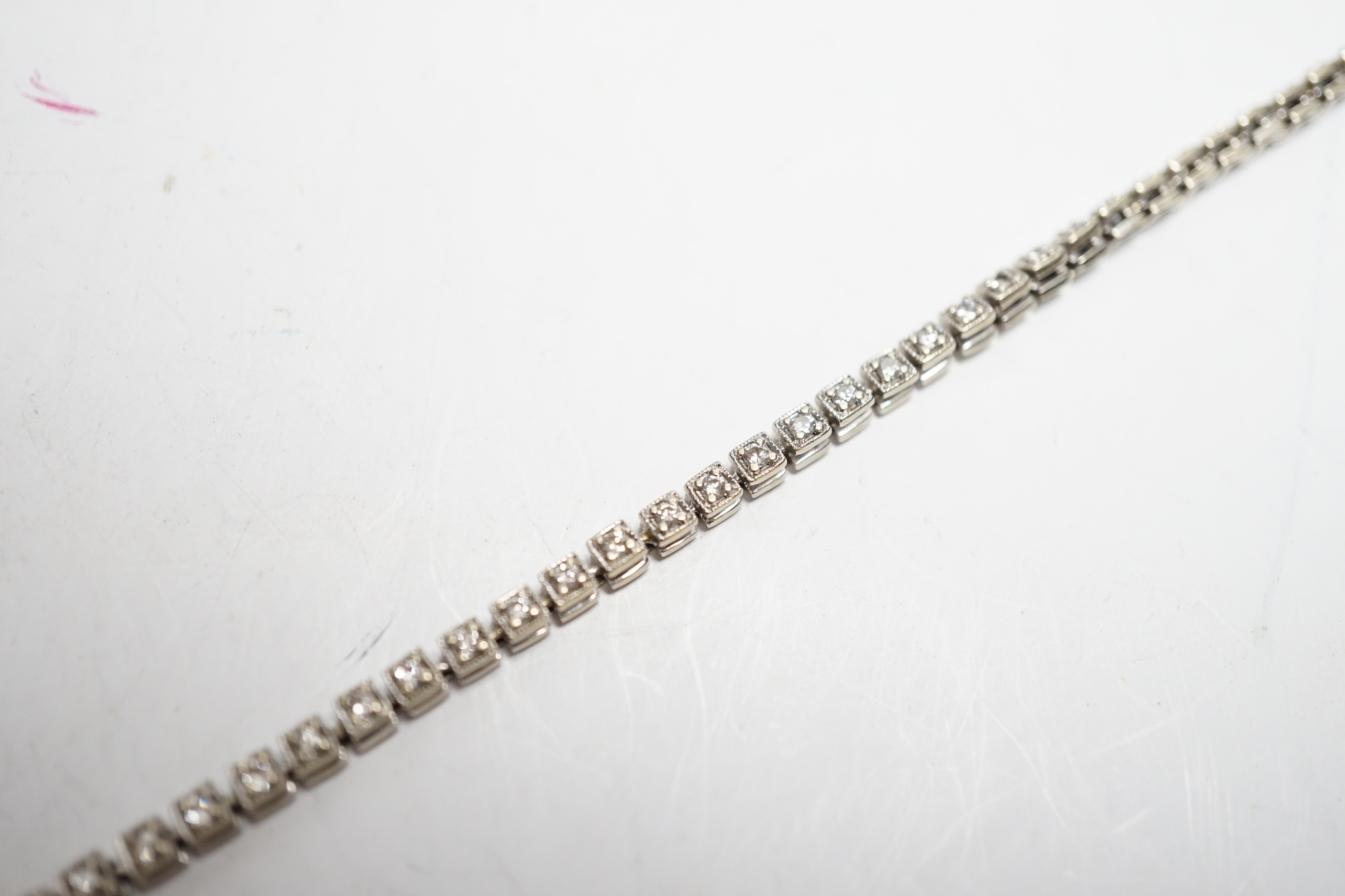 A 750 white metal and diamond line bracelet, set with sixty small stones, 20.8cm, gross weight 12 grams.